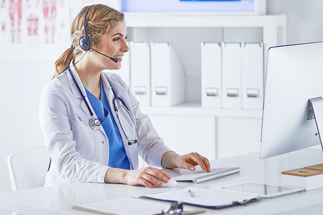 Image of doctor and keyboard using a headset to speak to a patient